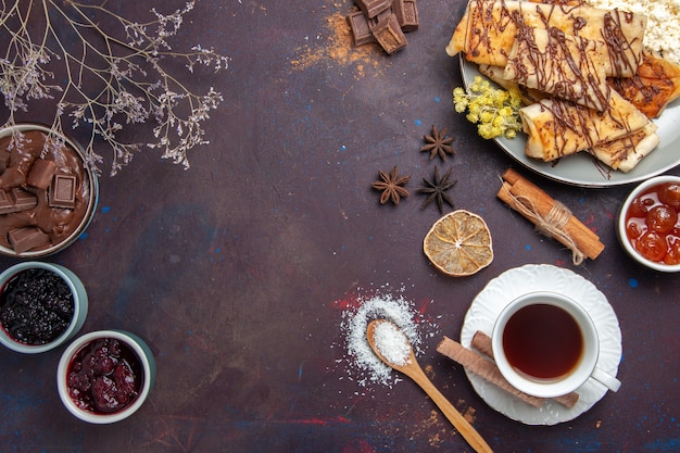 Draufsicht leckeres süßes Gebäck mit Tasse Tee und Marmelade auf dunklem Hintergrund Gebäckkekskuchenzuckersüßtee