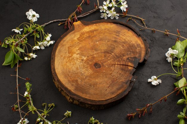 Draufsicht leeren Schreibtisch aus Holz zusammen mit weißen Blumen auf dem dunklen Hintergrund