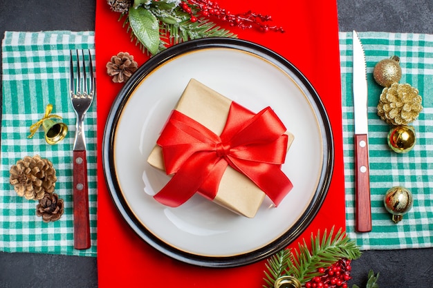 Draufsicht leerer Teller mit Geschenk- und Weihnachtsspielzeug und Gabel auf dunklem Hintergrund