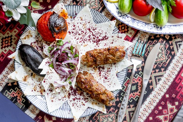 Draufsicht Lula Kebab auf Fladenbrot mit Auberginen und Tomaten mit Zwiebeln gegrillt