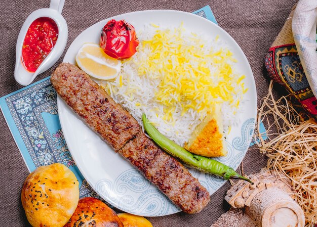 Draufsicht Lula Kebab mit Reis-Tomate und grünem Pfeffer gegrillt mit einer Scheibe Zitrone und Sauce