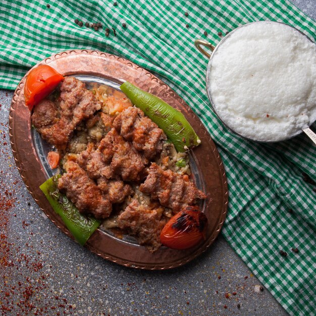 Draufsicht Lule Kebab unter Auberginensalat mit Tomate und Papier und Ayran