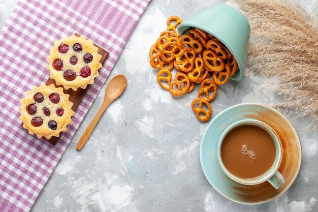 Draufsicht Milchkaffee mit kleinen Kuchen und Crackern auf dem hellen Hintergrundkuchenkeks süßer Zuckerauflauf