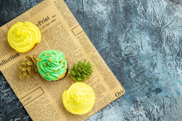 Draufsicht Mini Cupcakes Weihnachtsschmuck auf Zeitung auf dunkler Oberfläche