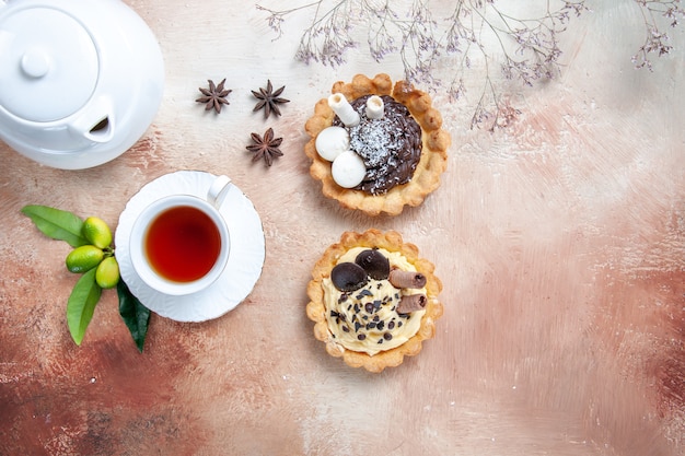 Draufsicht nahaufnahme süßigkeiten zwei cupcakes teekanne eine tasse tee