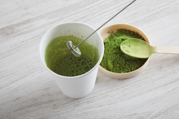 Draufsicht nehmen weißes Papierglas und Premium-Bio-Japan-Matcha-Tee auf Holztisch weg, bereit für moderne Art Lattezubereitung