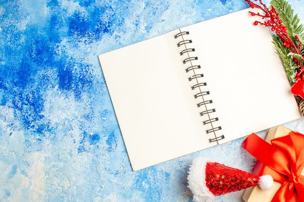 Draufsicht Notizbuch Weihnachtsgeschenk Weihnachtsmütze auf blauem Tisch freien Platz