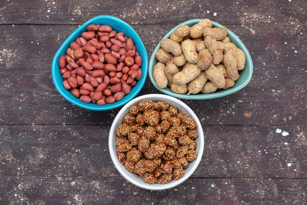 Kostenloses Foto draufsicht nüsse innerhalb platten verschiedene nüsse zusammensetzung auf dem hölzernen schreibtisch nuss erdnuss snack foto