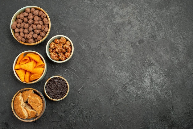 Draufsicht Nüsse und Chips in kleinen Töpfen auf dunkelgrauem Snack-Chip in Schreibtischfarbe