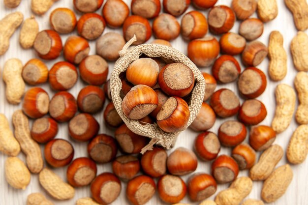 Draufsicht Nuss Zusammensetzung frische Haselnüsse und Erdnüsse auf weißem Schreibtisch Nuss Snack Erdnuss Walnuss