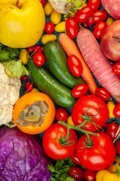 Draufsicht Obst und Gemüse Karotte Blumenkohl Kaki Rettich Kirschtomaten Rotkohl Tomaten auf blauem Hintergrund