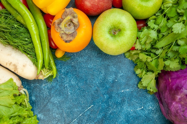 Draufsicht Obst und Gemüse Koriander Apfel Kaki Rotkohl Rettich Dill Salat Peperoni auf blauem Tisch mit freiem Platz