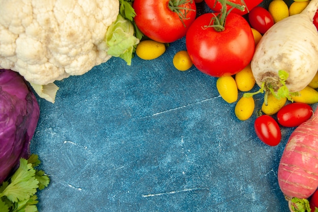 Draufsicht Obst und Gemüse Rotkohl Kirschtomate Cumcuat Tomate Rettich Blumenkohl auf blauem Tisch