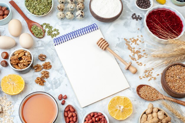 Draufsicht offener Notizblock mit Eiermehlgelee verschiedene Nüsse und Samen auf einem weißen Nussteigfarbkuchen süßer Kuchenfotozucker