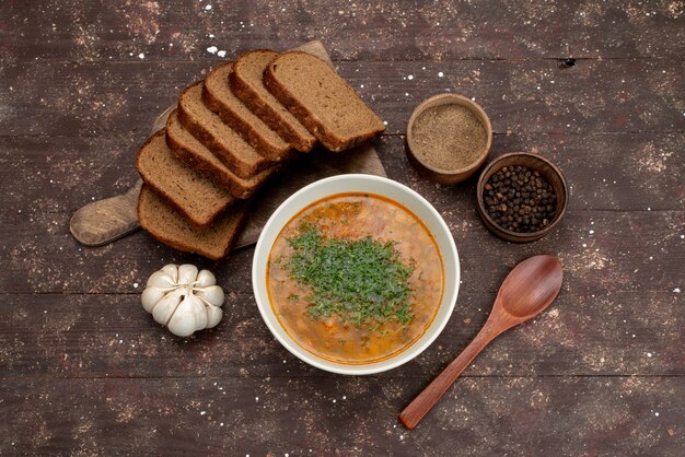 Draufsicht-Orangengemüsesuppe mit Brotlaib und Knoblauch auf braunem Nahrungsmittelsuppenbrot