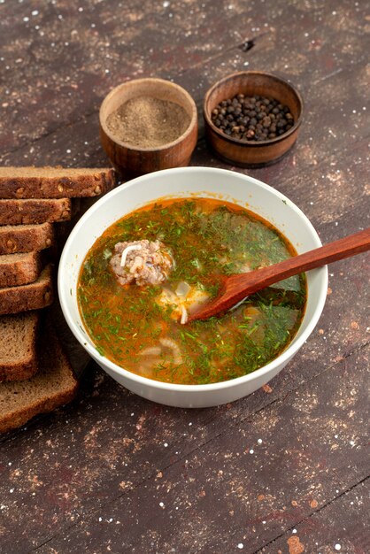 Draufsicht-Orangengemüsesuppe mit Brotlaibgrün und Knoblauch auf braunem Nahrungsmittelsuppenbrot