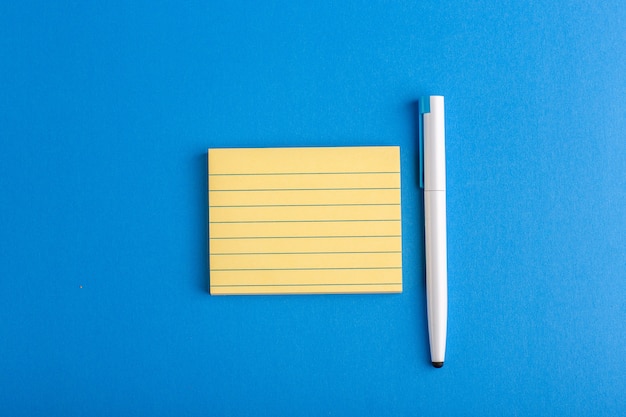 Draufsicht-Papieraufkleber mit Stift auf blauer Oberfläche