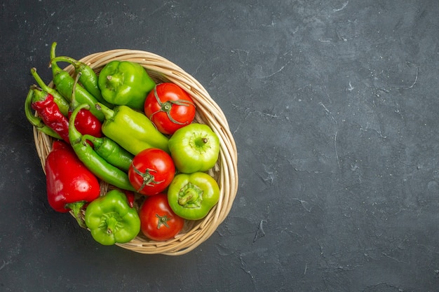 Draufsicht Paprika und Tomaten in Weidenkorb Schüssel auf dunkler Oberfläche freien Raum