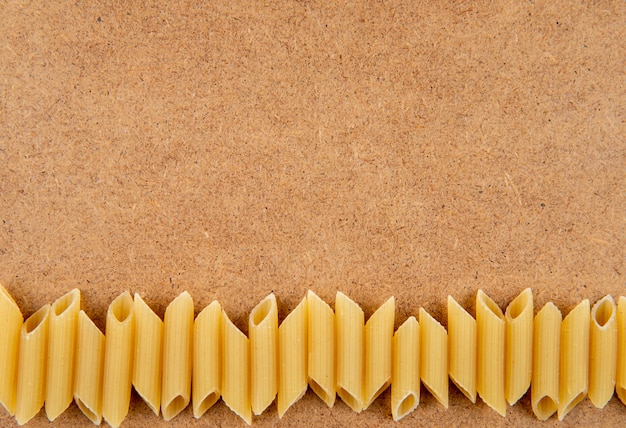 Draufsicht Penne Pasta auf der Unterseite mit Kopienraum auf braunem Hintergrund