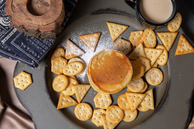 Draufsicht Pfannkuchen und Chips mit Milch auf dem grauen Hintergrundnahrungsmittelmahlzeitfrühstücks süßes Dessert