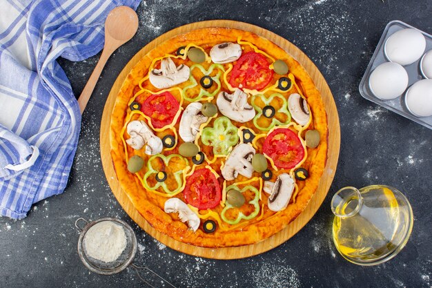 Draufsicht Pilzpizza mit Tomatenolivenpilzen mit Mehl auf dem grauen Schreibtischpizzateig italienisches Essen