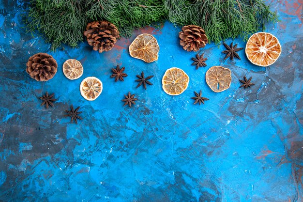 Draufsicht Pine Tree Branches Kegel getrocknete Zitronenscheiben Anissamen auf blau-roter Oberfläche