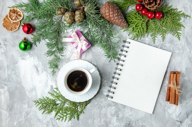 Draufsicht Pine Tree Branches Tasse Tee kleine Geschenke Weihnachtsbaum Spielzeug Notebook Zimt auf grauer Oberfläche