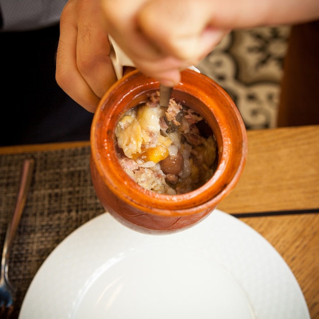 Draufsicht Piti mit weißer Platte und Gabel und menschlicher Hand im Tonkrug