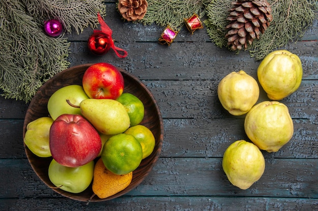 Kostenloses Foto draufsicht reife quitten mit frischen früchten auf dunkelblauem rustikalem schreibtisch viele frische pflanzen reifer obstbaum