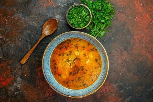 Draufsicht Reissuppe in Schüssel gehackte Grüns in Schüssel Petersilienbündel Holzlöffel auf dunkelrotem Tisch