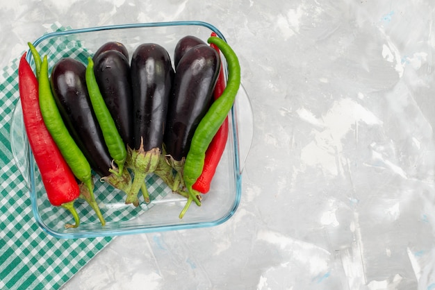 Draufsicht rohe Auberginen mit farbigen Paprikaschoten auf der hellen Schreibtischgemüsemahlzeitmahlzeit