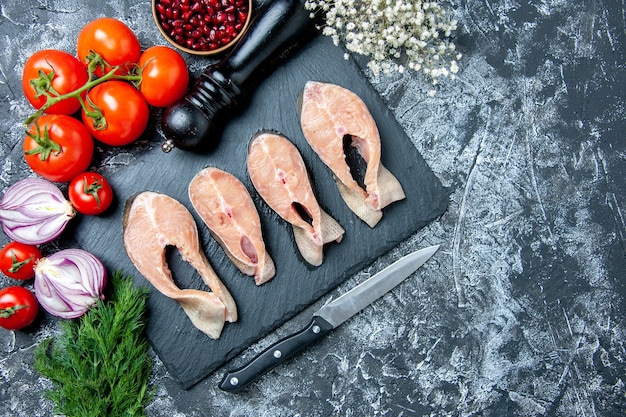 Kostenloses Foto draufsicht rohe fischscheiben auf tafel dill granatapfelkerne tomaten messer pfeffermühle auf tischkopierplatz