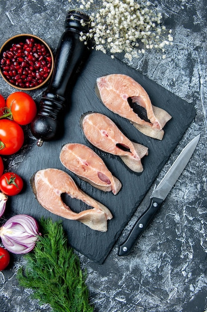 Draufsicht rohe Fischscheiben auf Tafel Dill Granatapfelkerne Tomaten Pfeffermühle auf Tisch