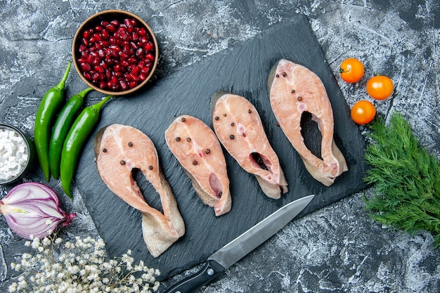 Draufsicht rohe Fischscheiben auf Tafelmesser Gemüse Meersalz auf grauem Hintergrund