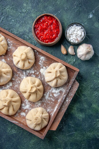 Draufsicht rohe kleine Knödel auf einem dunklen Tischmahlzeitfarbgeschirrteigfleisch, das Mehl kocht