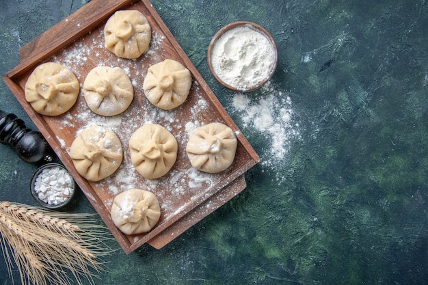 Draufsicht rohe kleine Knödel mit Fleisch innen auf dunklem Hintergrundfarbmahlzeitgericht, das Mehlteigfleisch kocht