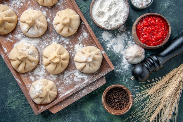 Draufsicht rohe kleine Knödel mit Fleisch innen auf dunklem Oberflächenfarbmehlgericht, das Mehlteig kocht