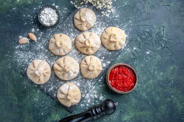 Draufsicht rohe kleine Knödel mit Fleisch innen auf dunkler Oberfläche Mehl Fleisch Pfeffer Farbe Kochmahlzeit Küche Gericht Teig