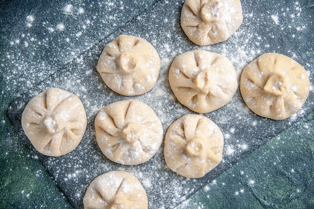 Draufsicht rohe kleine Knödel mit Fleisch innen auf einer dunklen Oberfläche Fleischfarbe Gericht rohe Mahlzeit Küche Teigmehl kochen