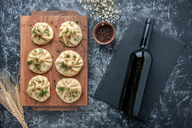 Draufsicht rohe kleine Knödel mit Fleisch und Flasche Wein auf grauer Oberfläche Teig Mahlzeit Kuchen Abendessen Küche Fleisch Kochgericht