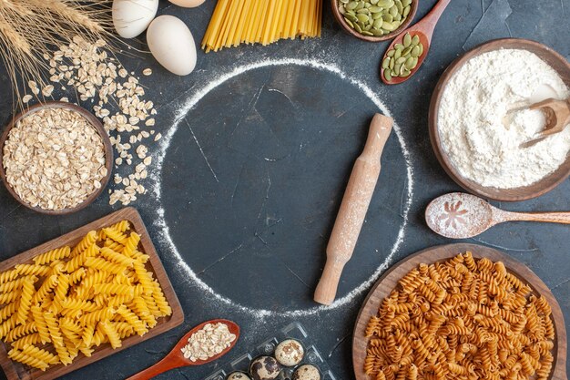 Draufsicht rohe Nudeln mit Müsli und Eiern auf dunklem Hintergrund Lebensmittelteig Farbfoto Backküche Mahlzeit