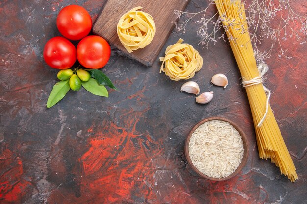 Draufsicht rohe Nudeln mit Reis und Tomaten auf der dunklen Oberfläche Nudelteig roh