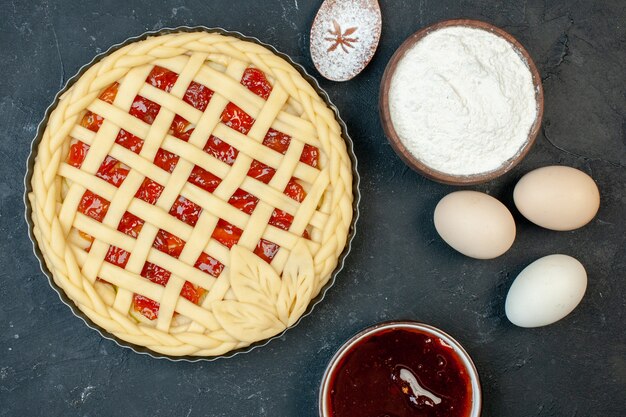 Draufsicht roher Obstkuchen mit Eiern und Mehl auf dunklem Hintergrund Kuchen backen Ofenfarbe süßer Keksplätzchenzucker