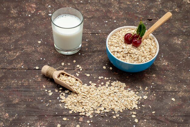 Draufsicht rohes Haferflocken innerhalb des weißen Tellers mit Milch auf braunem, rohem Gesundheitsfrühstück des Lebensmittels