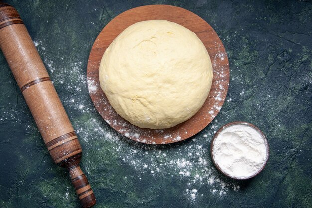 Draufsicht rohes Teigstück mit weißem Mehl auf dunkelblauem Hintergrund Gebäck backen Kuchenkuchen roher frischer Ofenteig Hotcake