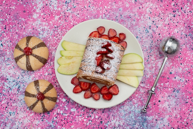 Draufsicht-Rollkuchen mit Erdbeeren und Äpfeln innerhalb der weißen Platte auf der farbigen Hintergrundkuchen-Keks-süßen Farbe