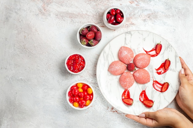 Kostenloses Foto draufsicht rosa erdbeerkuchen kleine köstliche süßigkeiten auf weißem hintergrund kekszucker tee süßer kekskuchen