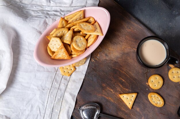 Draufsicht rosa Platte voll von Chips mit Milch auf dem grauen Hintergrund knusprige Cracker Snackfarbe