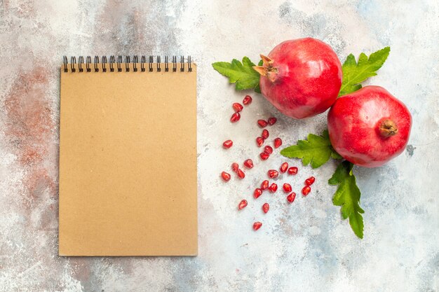 Draufsicht rote Granatäpfel Granatapfelkerne ein Notizbuch auf nackter Oberfläche