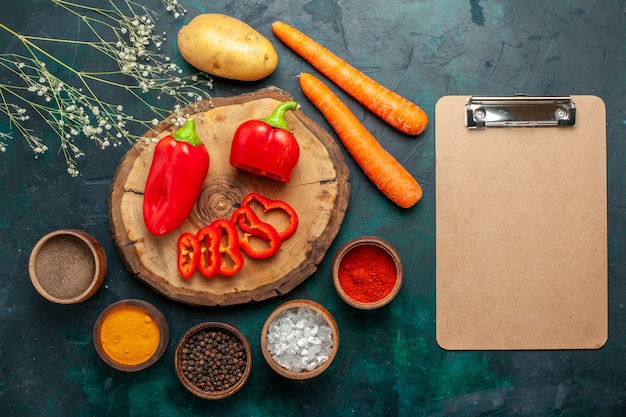 Kostenloses Foto draufsicht rote paprika mit verschiedenen gewürzen auf dunkelgrüner oberfläche gemüse scharf scharfes essen